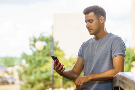 Handsome man using mobile phone, texting on smartphone outdoor in park. Technology and communication.の写真素材