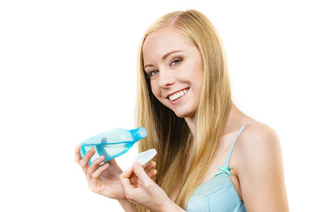 skincare. Young woman holding bottle with cleanser, cleaning skin with cotton swab pad. Girl taking care of her body.の写真素材