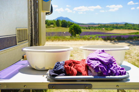 Doing laundry on vacation trip. Bowls with clothes at caravan vehicle. Camping on nature.の写真素材
