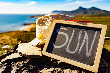 Black board with word sun against spanish sea coast. Landscape of Calblanque Park in Murcia Spain. Travel, vacation and prevention of vitamin D deficiency.の写真素材