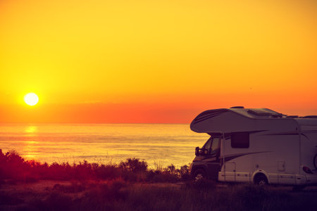 Sun rising over sea horizon, day break and caravan parking on beach sea shore. Travel with mobile home.の写真素材