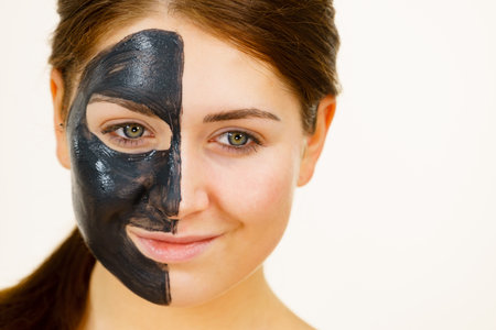 skincare. Woman with charcoal facial mask, deep cleanser on half face. Beauty, spa and acne treatment.の写真素材