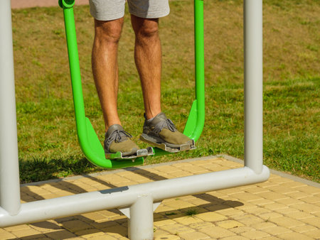 Working out in an outdoor gym. Male doing legs exercises on street simulators. Staying fit and healthy.の写真素材