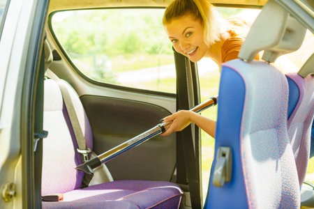 Woman hoovering seat of car. Auto interior cleaning with vacuum cleaner.の写真素材