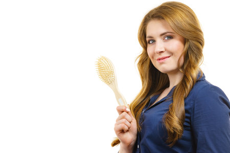 Young woman combing long healthy brown hair, using brush. Haircareの写真素材