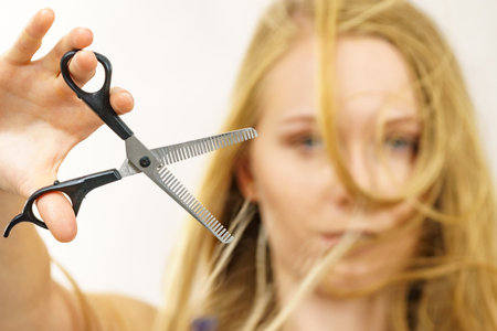 Young woman holding special chunking shears, tool for work of hairdresser. Coiffure hairstyle and haircut.の写真素材