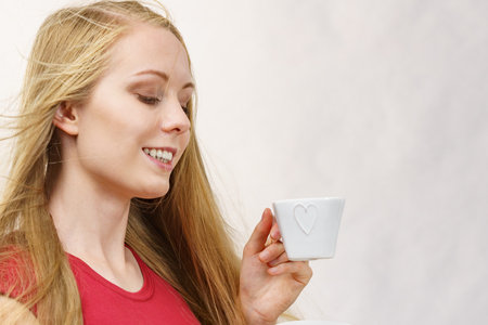 Blonde long hair woman with heart shaped coffee cup. Time to wake up, switching on. copy space.の写真素材