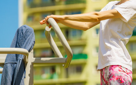 Young woman working out outside. Girl making exercises and training on public equipment in outdoor gym at park. Healthy lifestyle.の写真素材