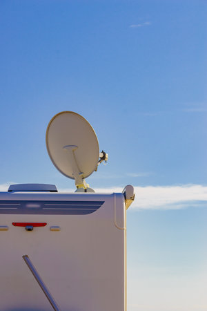 Satellite dish on roof of camper car against blue sky. TV connection. Travel holidays in motor home.の写真素材