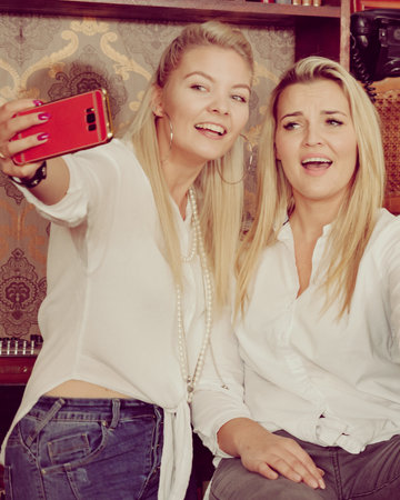Happy girls best friends in pub taking self photo with phoneの写真素材