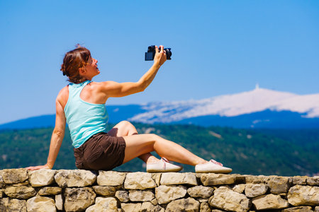 Tourist mature woman take travel picture from mountain landscape in Provence France. Mount Ventoux on the horizon.の写真素材