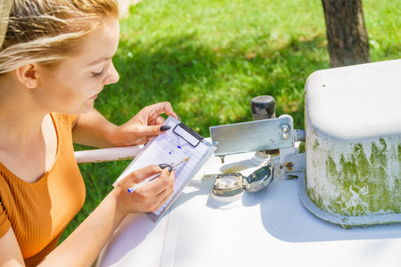 Woman checking level of propane gas in outside home fuel tank. House heating.の写真素材