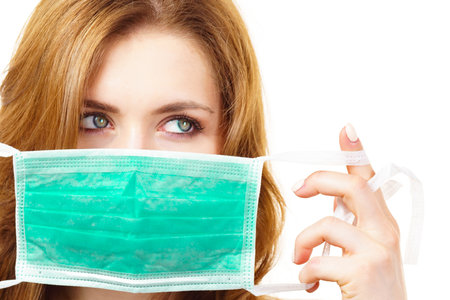 Woman using protective face mask, covering mouth. Coronavirus prevention. Healthcare medical hygiene concept.の写真素材