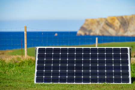 Single solar photovoltaic panels, charging batteries outdoors against sea landscape. Camping trip. Renewable eco energy conceptの写真素材