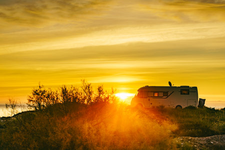Sun rising over sea horizon and camper rv camping on beach seashore. Holidays in Spain, travel with motor home.の写真素材
