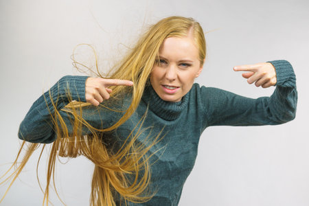 Angry young woman pointing with fingers. Frustrated face expression, hair blowing.の写真素材