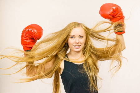 Blonde long hair woman wearing big red gloves standing with arms up, celebrating success. Female fight for equal rights for women.. Gender equality concept.の写真素材