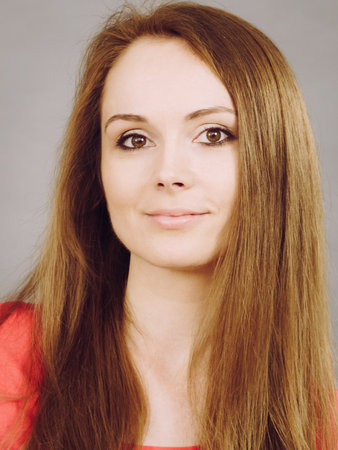 Portrait of young brunette woman, studio shot on greyの写真素材