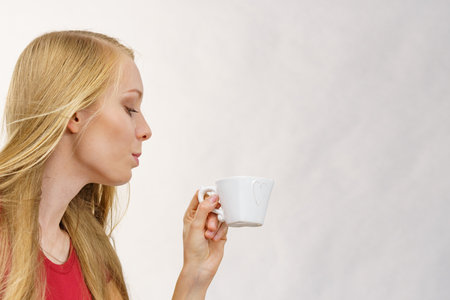 Blonde long hair woman with heart shaped coffee cup. Time to wake up, switching on. copy space.の写真素材