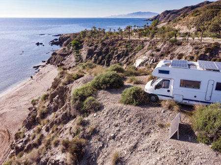 Aerial view. Caravan with solar photovoltaic panels on roof camping on cliff sea coast. Mediterranean region of Villaricos, Almeria, eastern Andalusia, Spain.の写真素材