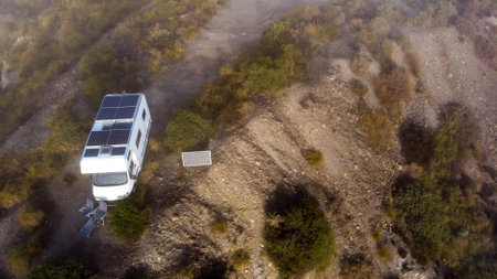 Aerial view. Camper with solar photovoltaic panels on roof camping on nature. Electricity on caravan vacation.の写真素材