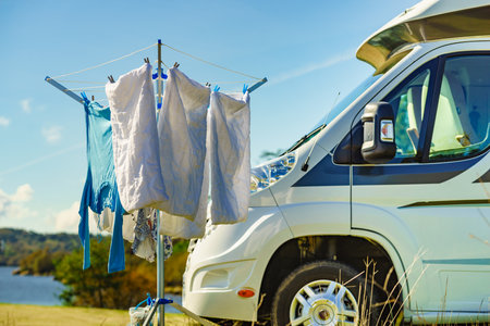 Camping on nature, road trip. Laundry clothes hanging to dry outdoor by camper car.の写真素材