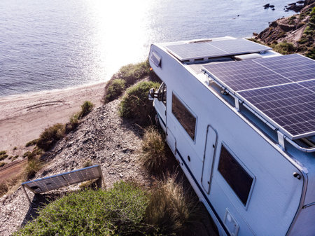 Aerial view. Caravan with solar photovoltaic panels on roof camping on cliff sea coast. Mediterranean region of Villaricos, Almeria, eastern Andalusia, Spain.の写真素材