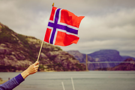 Female tourist with Norwegian flag enjoying fjord Lysefjord view. National route Ryfylke. Vacation...