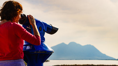 Woman using sightseeing binoculars, tourist telescope, overlooking Las Salinas landscape in Cabo de Gata Nijar Natural Park, Andalucia Spain. Place to visit. Tourismの写真素材