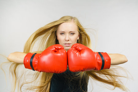 Blonde long hair young woman in big red gloves boxing, playing sports. Female fight for equal rights for women.の写真素材