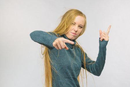 Young woman pointing at you and weighing her finger. Rejecting gesture, disagree sign. Serious face expression.の写真素材