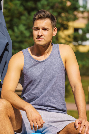 Handsome guy relaxing after outdoor workout. Fit man feeling healthy, enjoying sun. Exercising on...