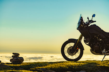 Motorcycle on mountain top above clouds.