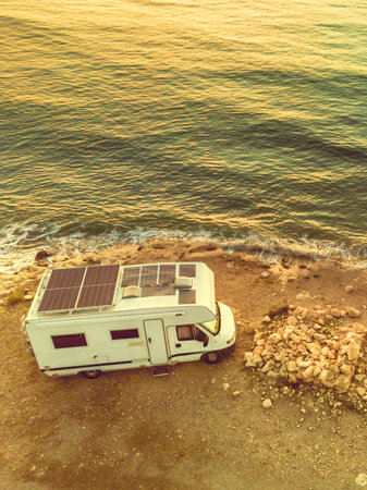 Caravan with solar panels on roof camping on coastal cliff. Mediterranean sea in Spain.の写真素材