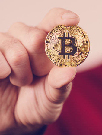 Man hand holding golden bitcoin coin sign, digital symbol of new virtual currencyの写真素材