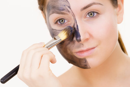 Woman being applying clay carbo detox mask to her face, using brush accessory. Beauty treatment. Skincare.の写真素材