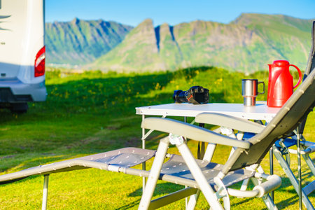 Camp table with thermos and thermal mug, norwegian mountains in the background. Camping on nature.の写真素材