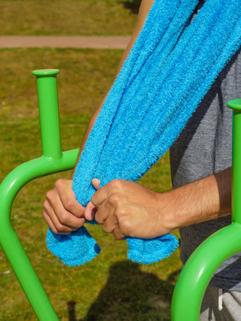 Handsome guy relaxing after outdoor workout. Fit man feeling healthy, enjoying sun. Exercising on public gym equipment in the open air.の写真素材