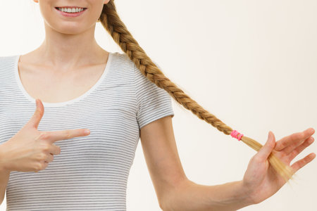 Blonde girl with long braid hair. Haircare, hairstyling, feminine style.の写真素材