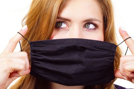 Woman using black protective reusable face mask, covering mouth. Coronavirus prevention. Health and safety.の写真素材