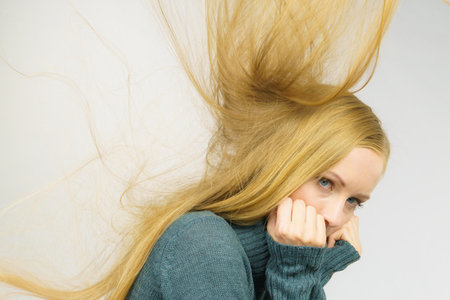 Sad melancholy young woman with blowing long blonde hair.の写真素材