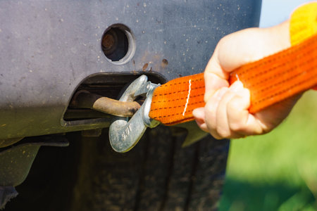 Male hand clings towing rope strap to tow hook in car.の写真素材