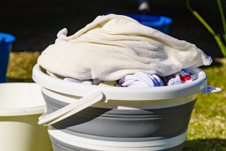 Doing laundry on vacation trip. Buckets with washing clothes outdoors on nature.の写真素材