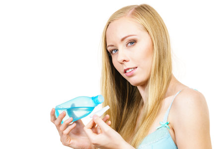 skincare. Young woman holding bottle with cleanser, cleaning skin with cotton swab pad. Girl taking care of her body.の写真素材