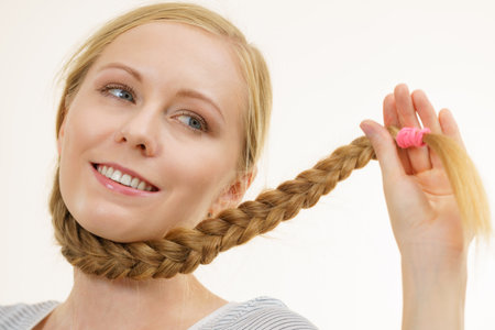 Blonde girl with long braid hair around the neck. Haircare, hairstyling.の写真素材