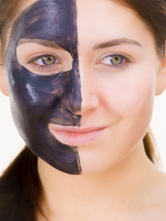 skincare. Woman with charcoal facial mask, deep cleanser on half face. Beauty, spa and acne treatment.の写真素材