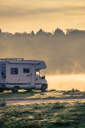 Caravan camping on lake shore in Portugal. Camper trip in autumn time. Foggy misty peace morning.の写真素材