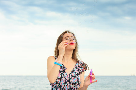 Happiness and carefree concept. Young woman having fun blowing soap bubbles outdoorの写真素材