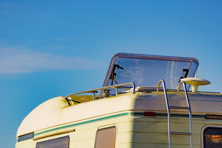 Rv camper vehicle with open sunroof, raisable panel window on roof top against blue sky. Traveling by motor home.の写真素材