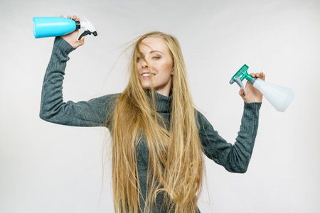 Young female messy long blonde hair holding bottle, applying hair spray.の写真素材